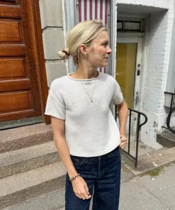 Kvinde iført PetiteKnit Cloud Tee striktrøje i lys farve udendørs